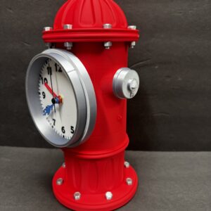 Bright red fire-hydrant-shaped tabletop clock with a round silver-rimmed white analog face on the side, black numerals, red minute hand and blue hour hand, and silver bolt accents against a dark gray background.