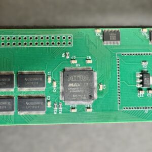 Top-down photo of a green PiStormSTE printed circuit board showing a central Altera MAX FPGA chip, four memory ICs in a 2x2 grid to the left, multiple pin-header holes and surface-mounted capacitors and resistors, an empty socket area on the right, and white silkscreen labels, set against a gray background.