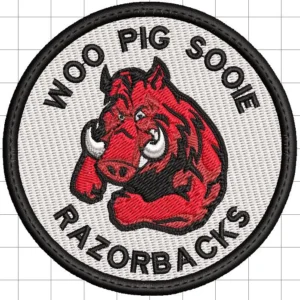 Circular embroidered patch showing a red razorback hog head in the center with black text reading WOO PIG SOOIE along the top and RAZORBACKS along the bottom on a white background and black border.